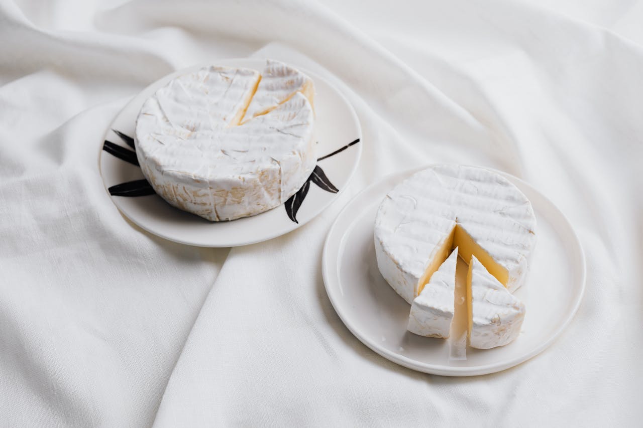 Close-up of gourmet Brie cheese on elegant plates, showcasing its creamy texture and refined presentation.