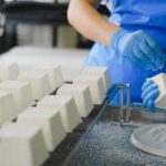 Worker making ricotta cheese in a food factory with precise technique.